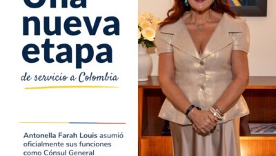 Antonella Farah Louis de pie en su despacho junto al anuncio Una nueva etapa de servicio a Colombia, como Cónsul General de Colombia en Miami